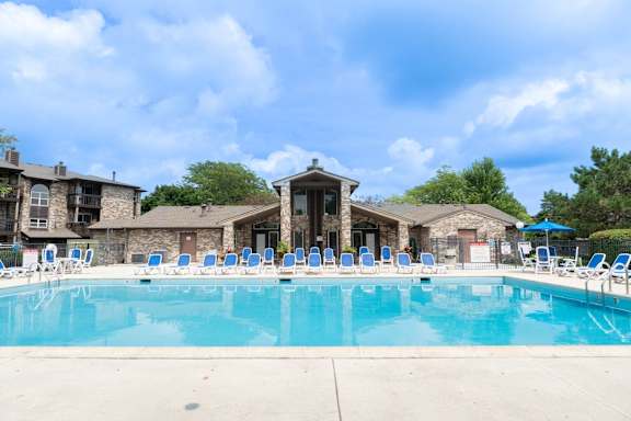 A large swimming pool with blue water and white lounge chairs.