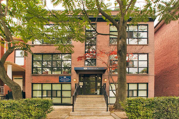 a brick building with stairs and trees in front of it