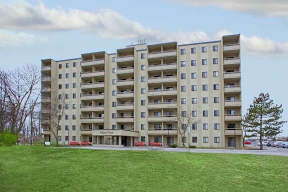 a large apartment building with a green lawn in front of it