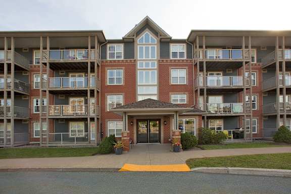 A large red brick building with a glass entrance and balconies on the second floor.