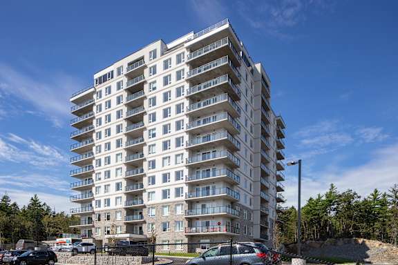 A large white apartment building with balconies on each floor.