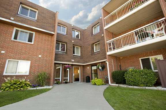 Apartment building with a balcony and a green lawn in front.