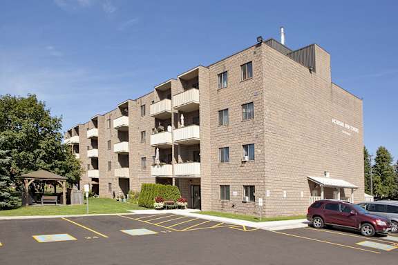 a brick apartment building with a red car parked in a parking lot