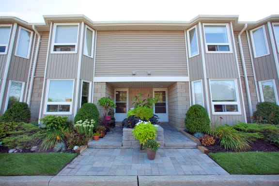 the front of an apartment building with a walkway and potted plants