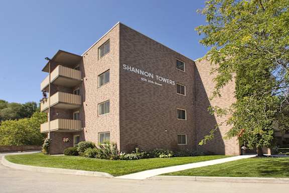a brick building with a lawn and trees in front of it