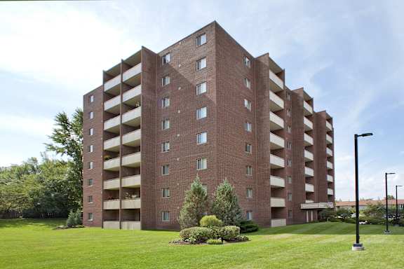 a tall brick building with balconies and a green yard