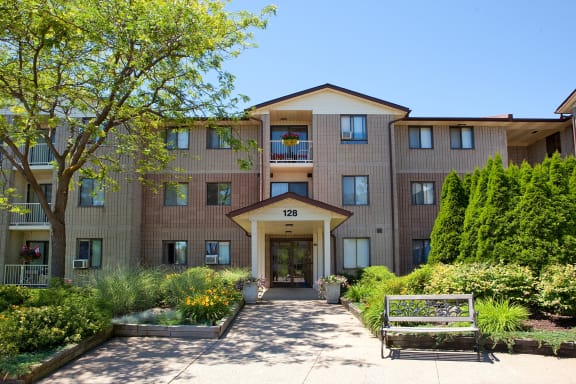 the front entrance of a building with a walkway and a bench