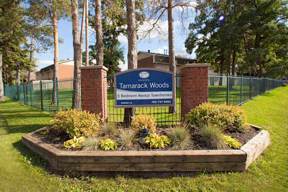 the sign for tamarack woods in front of a fence