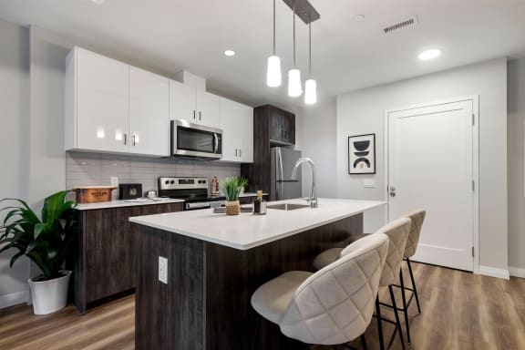 an open kitchen with an island with white quartz counter top and white cabinets