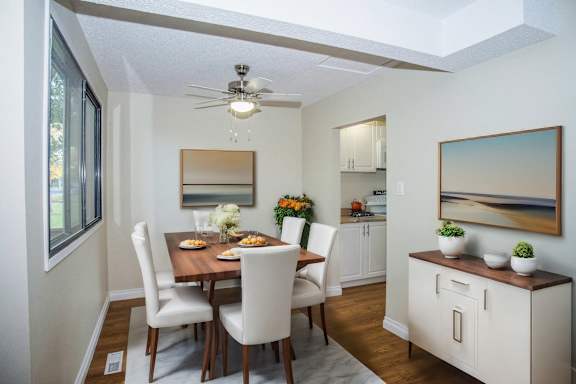 a dining room and kitchen with a table and chairs and a ceiling fan