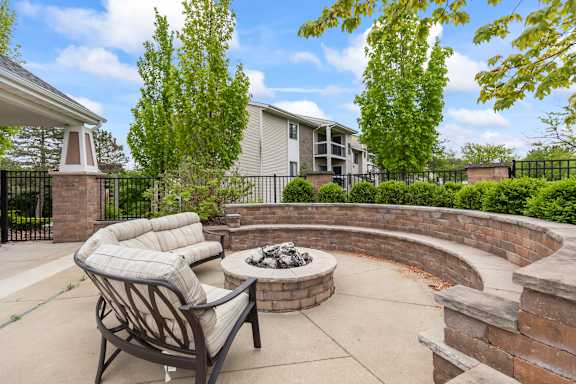 A patio with a fire pit and a chair.