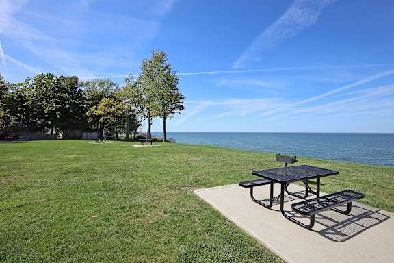 A picnic table is on a concrete slab in a grassy area.
