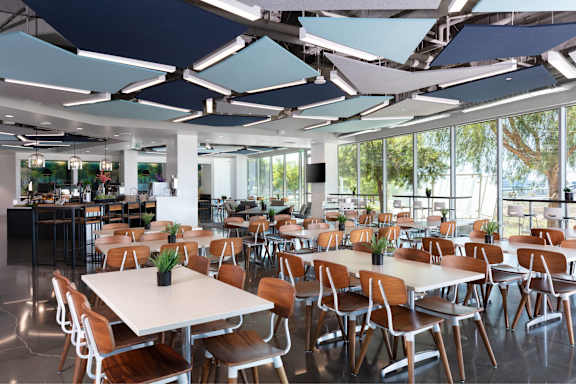 A modern cafeteria with tables and chairs and a bar area.