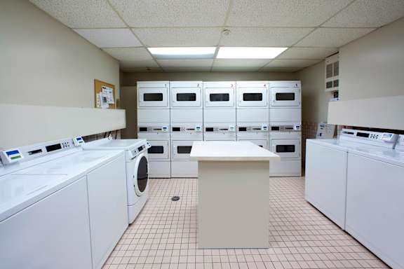 an empty laundry room with washers and dryers and a row of white machines