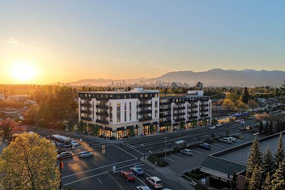 A sunset view of a city street with cars and buildings.