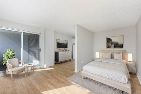 A bedroom with a large bed and a chair by the window.
