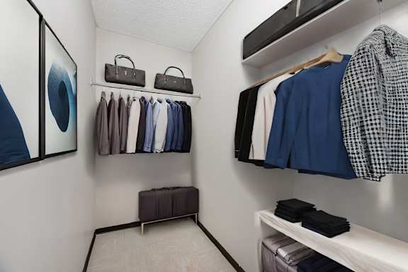 A white closet with a bench and a row of shirts hanging on a rail.