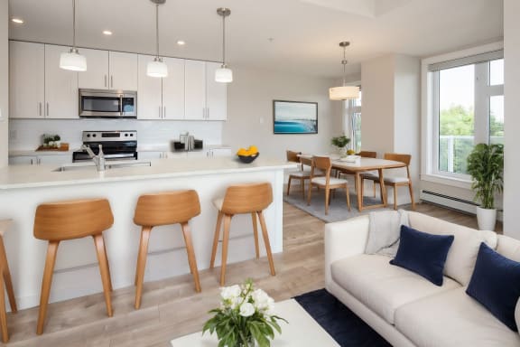 an open kitchen and living room with a white couch and wooden stools