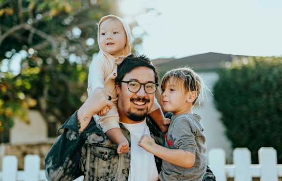 A man is carrying two children on his shoulders.at Quari Street Apartments, Colorado, 80011