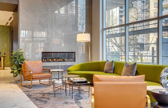 A modern living room with a fireplace and a green couch. at Citizen on Jasper, Edmonton, T5K 0M5