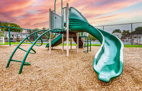 A playground with a green slide and a climbing frame.