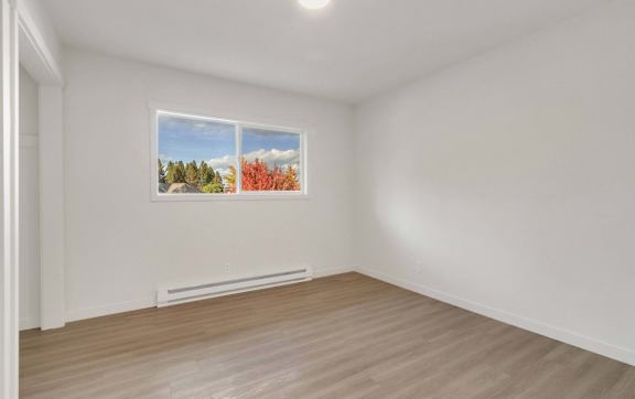 A room with a window and a picture of a forest on the wall.