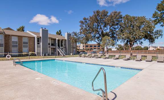 A swimming pool in front of a building with trees in the background.