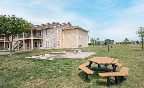 A picnic table sits in the grass in front of a building.