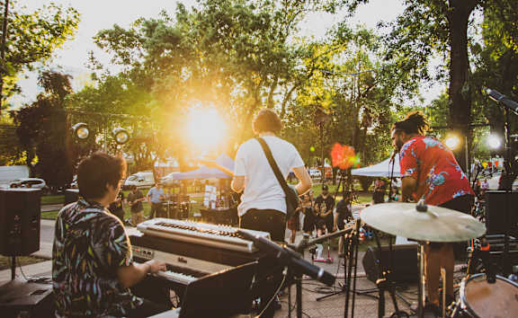 A group of people playing music in a park during sunset.