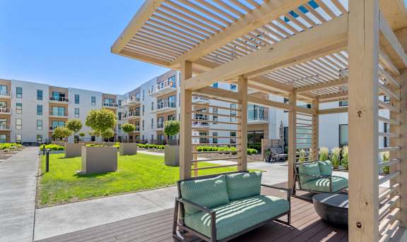 a patio with green chairs and a wooden pergola