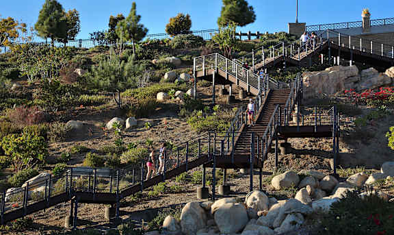 A group of people are walking up a staircase in a rocky landscape.