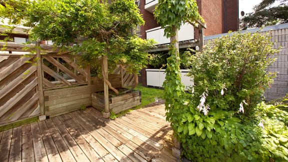 a backyard with a wooden deck and trees and bushes