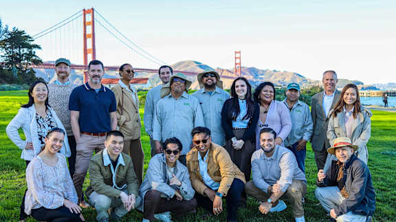 A group of people are posing for a photo in front of the Golden Gate Bridge.