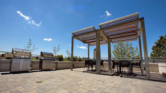a rooftop patio with tables and chairs and a barbecue grill