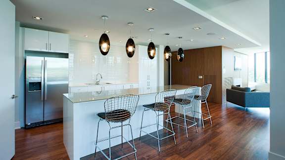 a large kitchen with a white counter top and bar stools