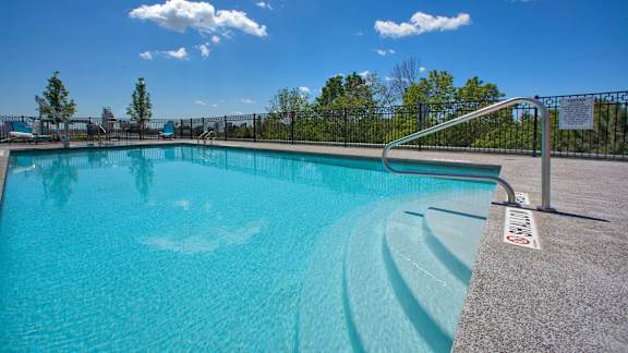 a swimming pool with a blue sky and trees in the background