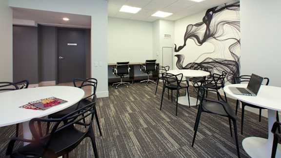 a classroom with tables and chairs and a mural on the wall