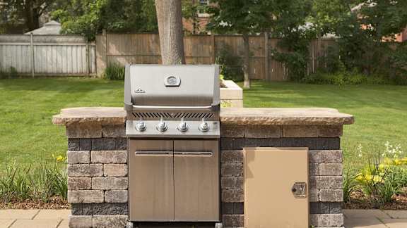 a barbecue grill in a backyard next to a tree