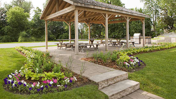 a pavilion with benches and flowers in a garden