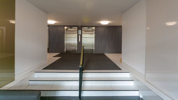 a lift lobby with stairs and a glass door