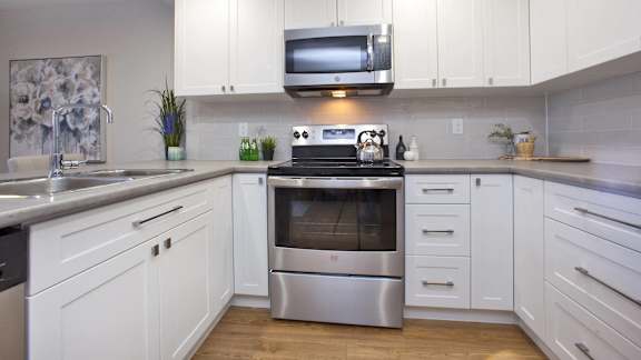 a white kitchen with stainless steel appliances and white cabinets
