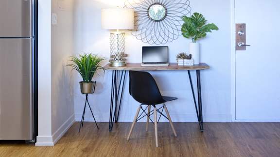 a home office with a laptop on a desk with a lamp and plants
