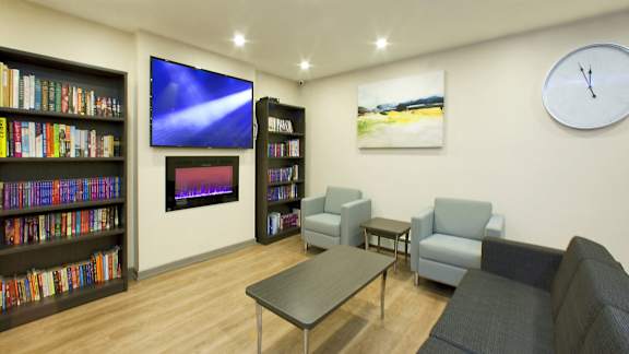 a library with a couch and a table and a clock on the wall