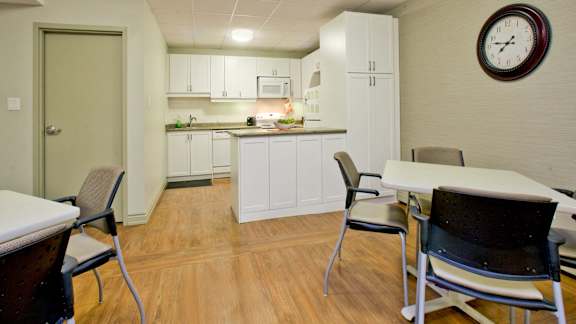 a dining room with a kitchen and a clock on the wall