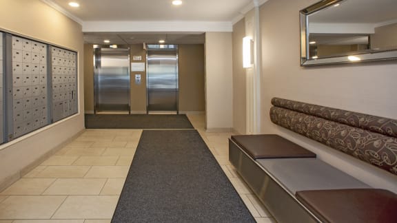 a hallway with benches and elevators and a mirror in a hotel lobby