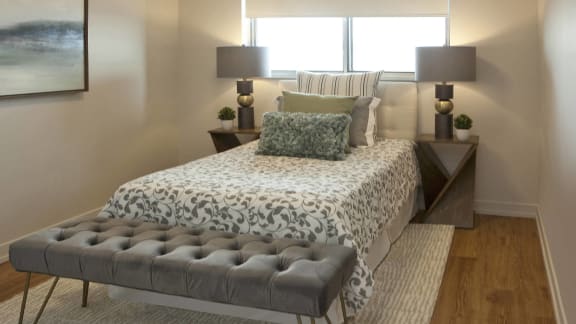 a bedroom with a bed and two lamps and a window