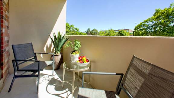 a balcony with two chairs and a table with fruit on it