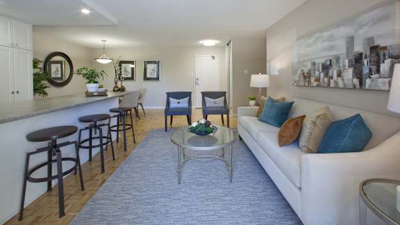 a living room with a couch and a coffee table and a kitchen with a bar