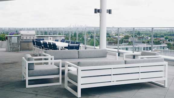 A white outdoor seating area with a view of the city.