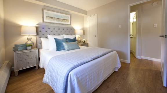 a bedroom with a bed and two nightstands and a door to a bathroom